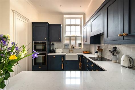 Dark Blue Kitchen Cabinetry With Brass Handles White Quartz Worktop