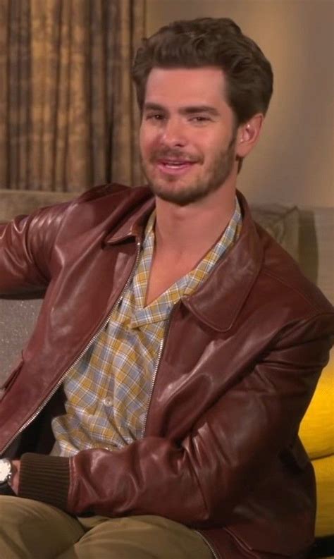 A Man In A Brown Leather Jacket Sitting On A Couch With His Hand On His Hip