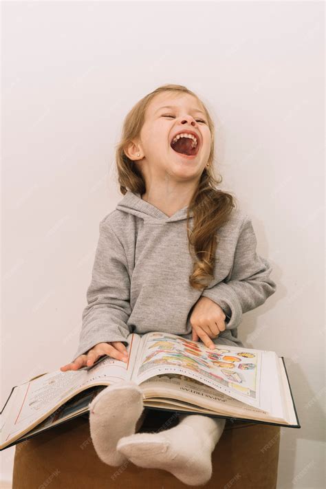 Free Photo Laughing Girl Reading Book On Pouf