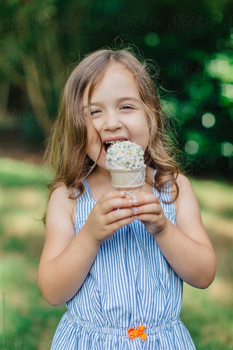 Cute And Happy Young Girl Eating Ice Cream Outside By Stocksy