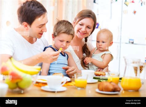 Los jóvenes feliz familia con dos niños de desayunar juntos en casa