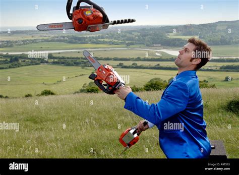 Young entertainer in blue suit juggling three orange chainsaws Stock ...