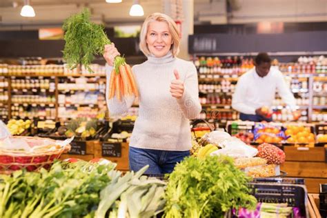 Portrait Of Satisfied Mature Woman Buying Fresh Organic Vegetables In