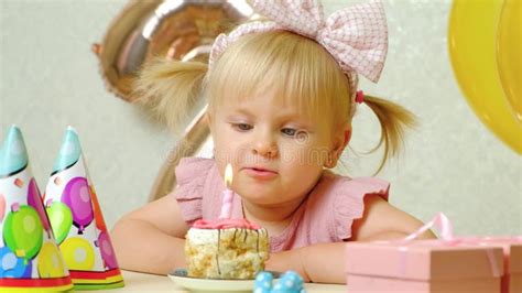 A Two Year Old Girl Blows Out A Candle On A Birthday Cake Makes A Wish