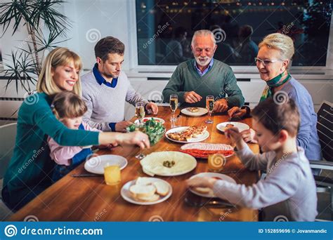 Familia Que Disfruta De La Comida Alrededor De La Tabla En Casa Foto De