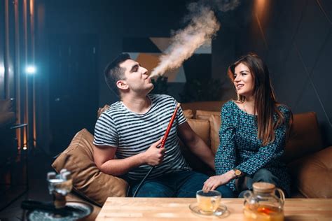 Premium Photo Young Couple Smoking Hookah On Leather Couch At The Bar