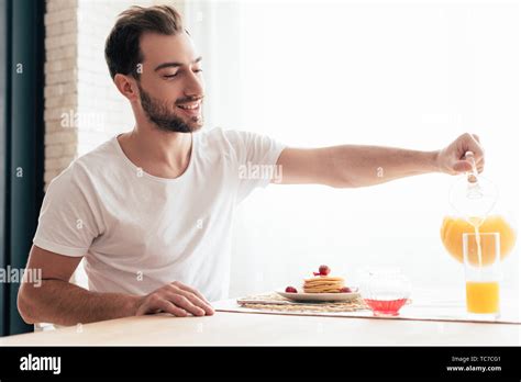 Smiling Bearded Man Pouring Orange Juice In Glass Stock Photo Alamy