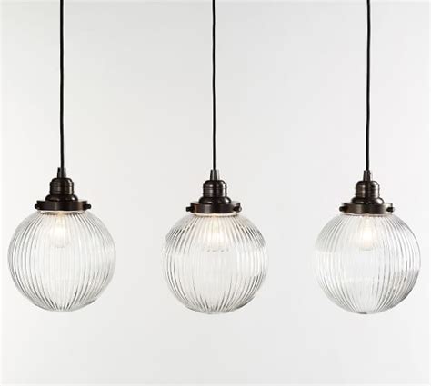 Three Clear Glass Globe Pendant Lights Hanging From Black Corded Cords