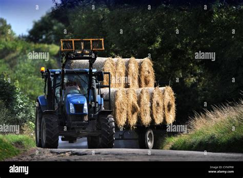 A Tractor Pulling A Trailer Of Hay Bales In Gloucestershire Uk Stock