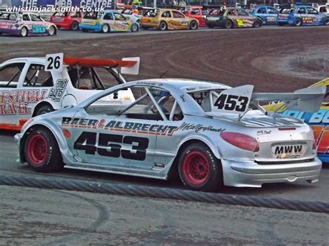 Two Race Cars Racing On A Track With Other Cars In The Background