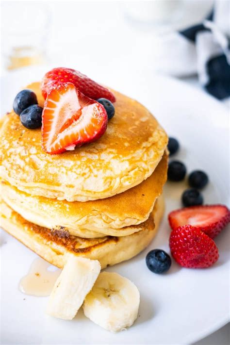 Fluffy Pancakes Served With Maple Syrup Strawberries Blueberries And Banana In A Plate With