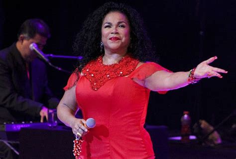 A Woman In A Red Dress Standing On Stage With Her Hands Out To The Side