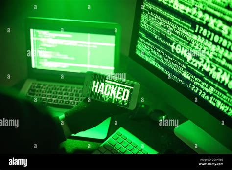 Hacker with mobile phone using computers in dark room Stock Photo - Alamy