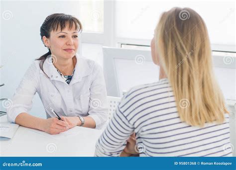 Friendly Female Doctor Comforting Middle Aged Patient In Hospital Stock