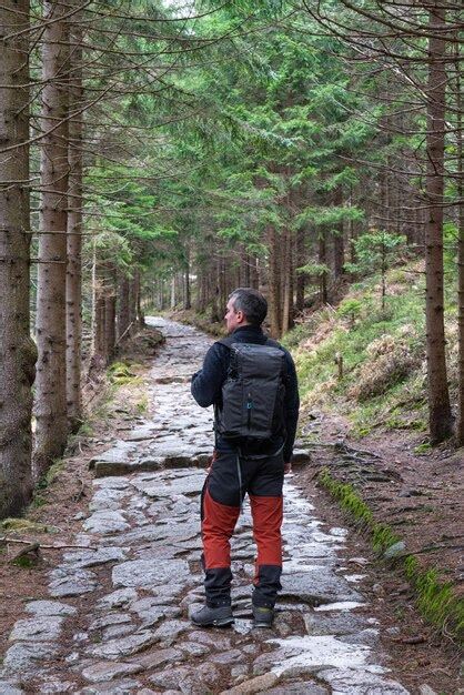 Premium Photo A Mature Man With A Backpack On His Back Walks Along A