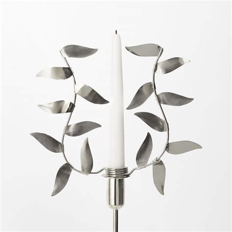 A White Candle Is Surrounded By Metal Leaves