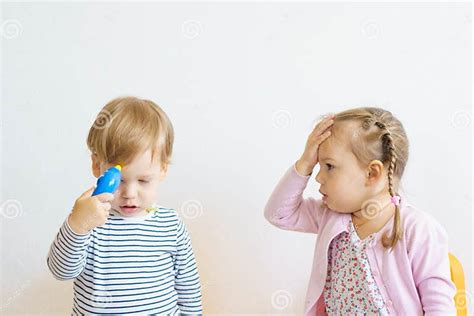 Two Children Play Doctor In The Nursery Brother In Yellow Glasses