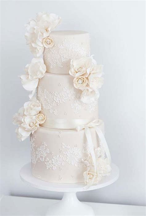 A Three Tiered Wedding Cake With White Flowers On Top