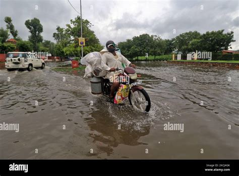 Commuters Wade Through A Waterlogged Street On A Rainy Day During The