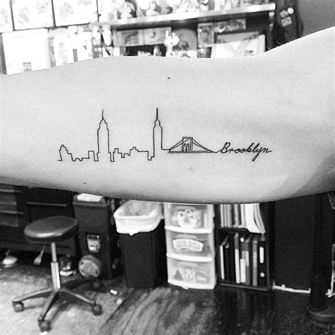 Brooklyn skyline tattoo on the right inner arm.