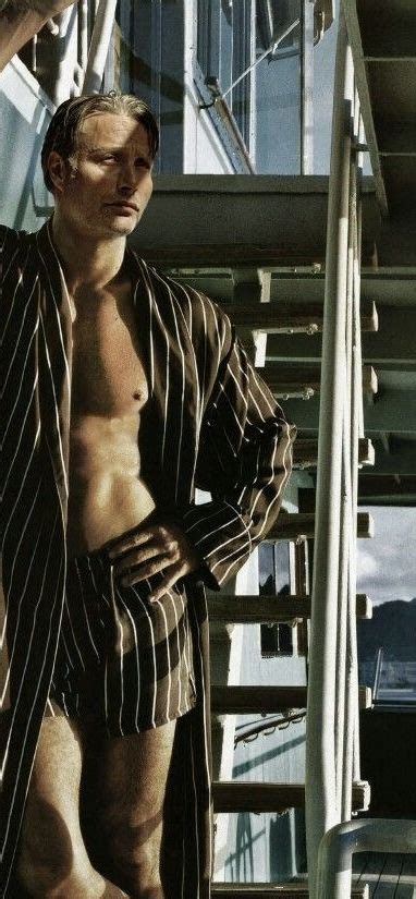 A Man With No Shirt On Standing In Front Of Some Stairs Wearing Striped