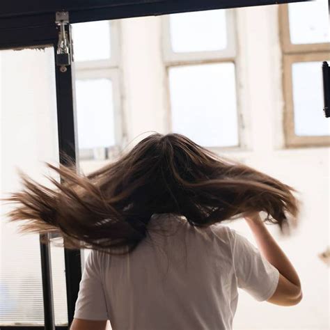 A Woman With Her Hair Flying In The Air And Looking Out An Open Window