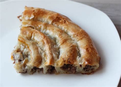 Two Pieces Of Meat And Cheese Pastry On A White Plate