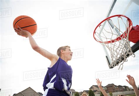 Caucasian boy dunking basketball in hoop - Stock Photo - Dissolve