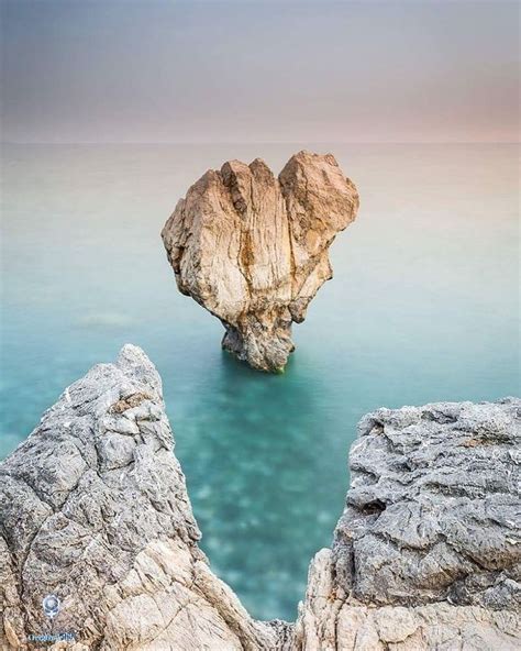 A Rock Sticking Out Of The Water Near Some Rocks