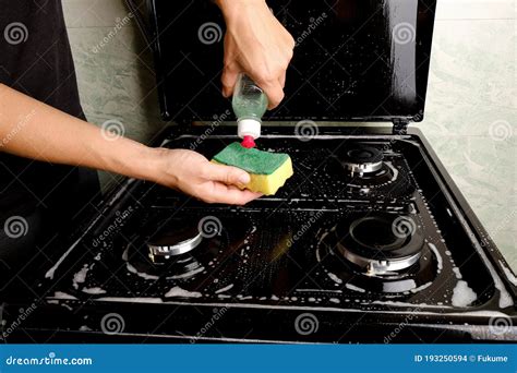 Cleaning The Gas Stove In The Kitchen With Detergent And A Sponge