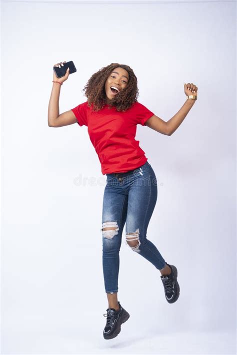 Vertical Shot Of A Happy Young Black Lady Jumping In Excitement And