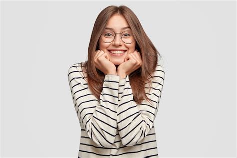 Filmación en interiores de mujer joven feliz con gafas posando contra