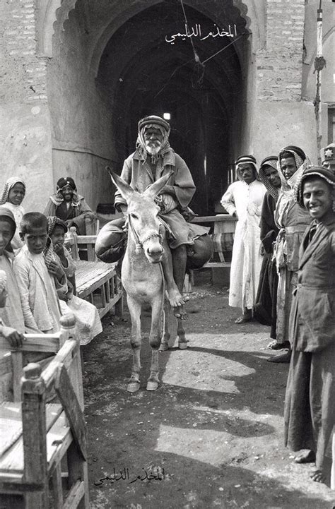 an old black and white photo of a man on a donkey in front of people