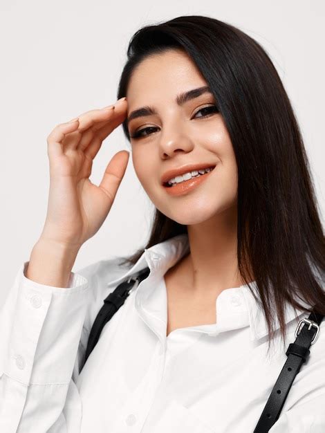 Premium Photo Happy Brunette Woman Touches Her Head With Her Hand And Smiles On A Light Background