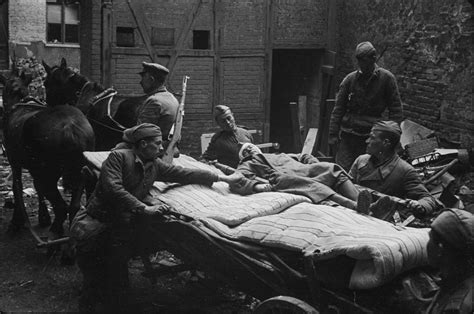Санитары укладывают раненого красноармейца на повозку во дворе ...