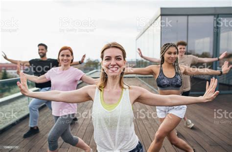 Group Of Young People Doing Exercise Outdoors On Terrace Sport And