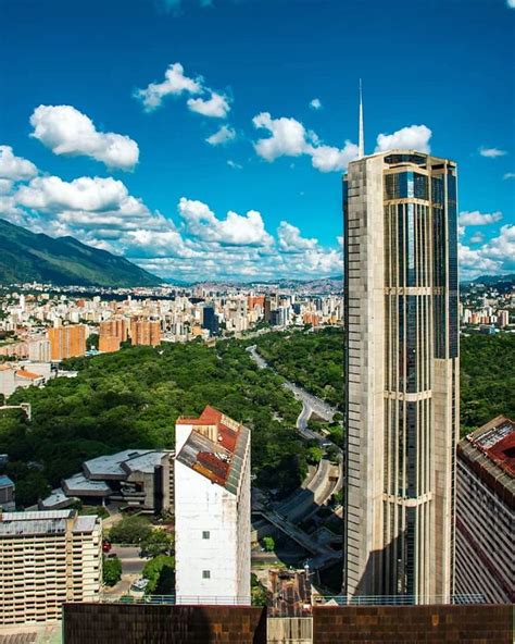 An Aerial View Of A City With Tall Buildings And Mountains In The Backgroud