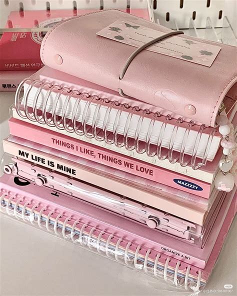 A Stack Of Pink Notebooks Sitting On Top Of A White Table Next To A