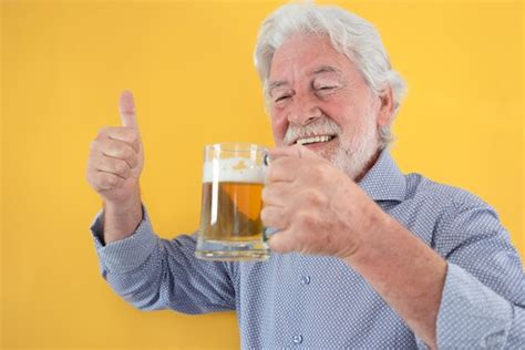 Homem sênior de cabelos brancos feliz segurando um copo de cerveja