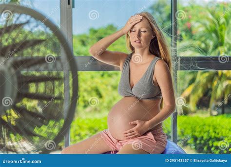 A Pregnant Woman Seeks Relief From An Abnormal Heatwave By Using A Fan