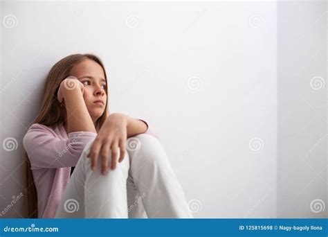 Jeune Fille Songeuse Dadolescent Sasseyant Par Le Mur Sur Le Plancher