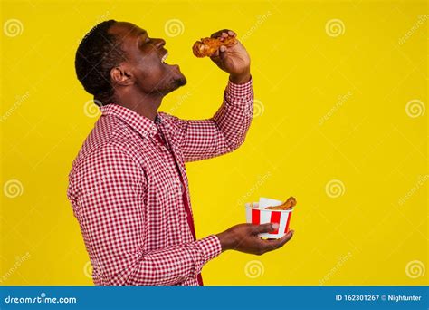 Funny African American Man Eating Fried Chicken Leg in Studio Yellow ...