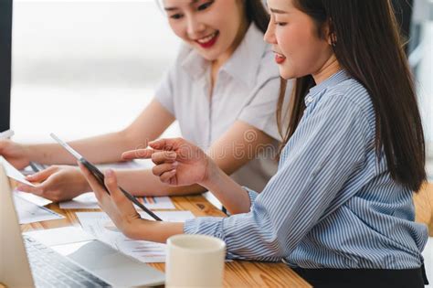 Two Engaged Businesswomen Using A Tablet And Discussing Work With Focus