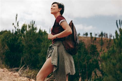 Glückliche Frau beim Wandern im Wald Frau trägt eine Tasche und geht