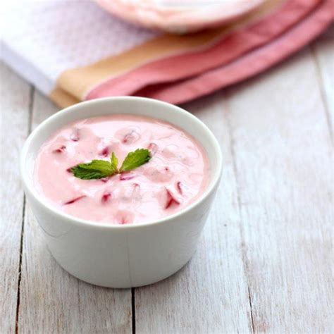 a white bowl filled with food on top of a wooden table next to a pink towel