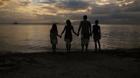 Schattenbild Der Familie Auf Dem Strand Am Sonnenuntergang Stock