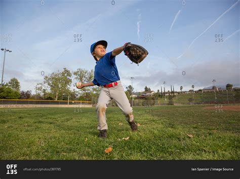 Boy throwing ball at practice on baseball field stock photo - OFFSET