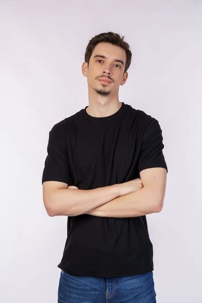 Retrato de jovem bonito vestindo camiseta preta em pé braços