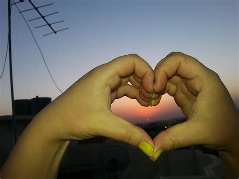 Premium Photo | Hands forming heart shape at sunset