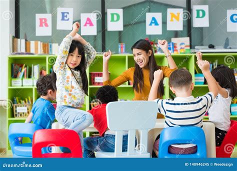 Happy Asian Female Teacher And Mixed Race Kids In Classroom